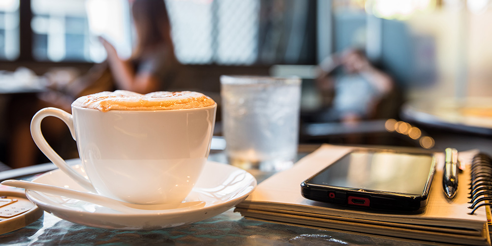 cup of coffee with a notebook, pen and smartphone