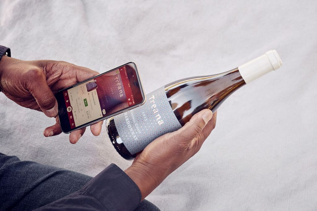 man taking a picture of a bottle of wine with the mobile