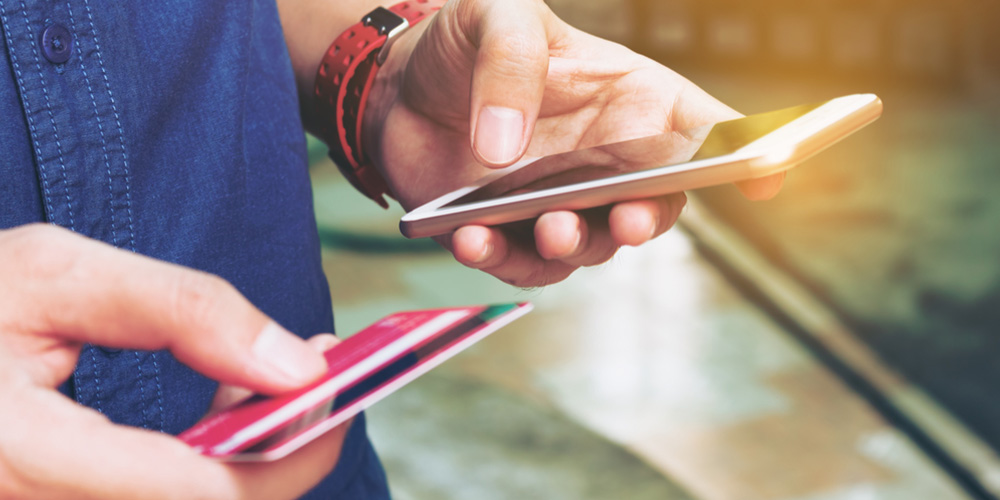 person holding their smartphone and a credit card