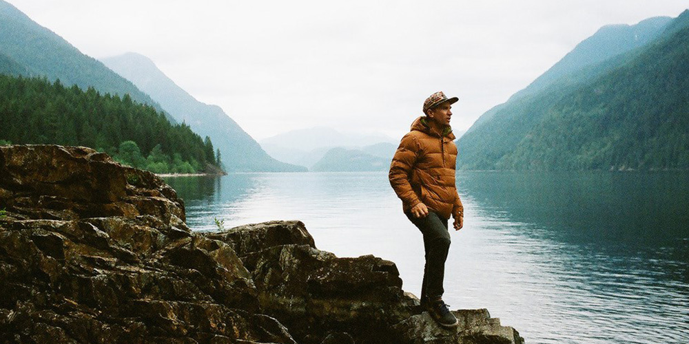 picture of a man standing on a rock by a lake