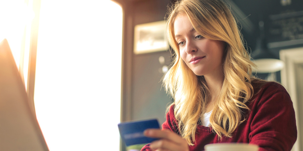 woman on her laptop with a credit card and mug of coffee