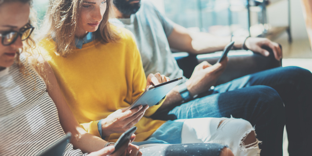 younger individuals looking at their phones and tablet
